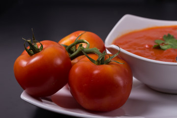 tomato soup with fresh tomatoes on black background