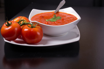 tomato soup with fresh tomatoes on black background