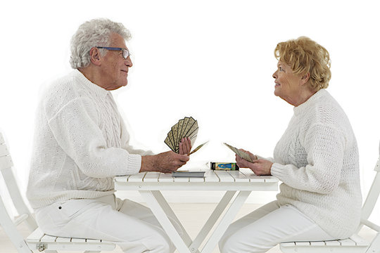 Happy old couple playing together with cards