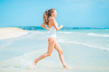 Fototapeta na wymiar Happy young woman in swimsuit running into sea