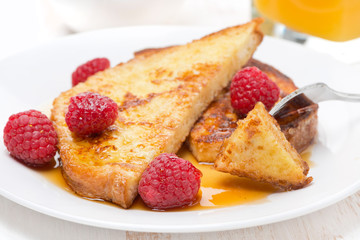 French toast with raspberries and maple syrup on a plate