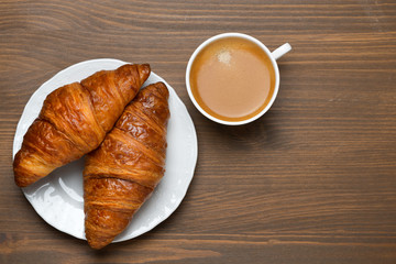 fresh croissants, cup of espresso on wooden background