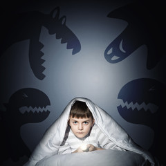 boy under the covers with a flashlight