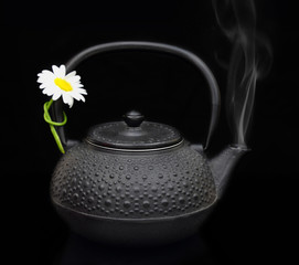 Obraz na płótnie Canvas Teapot with chamomile flower and smoke isolated on black