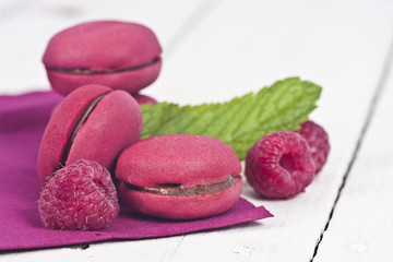 macaroons fresh raspberries on white wooden background
