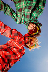 couple in ski suits with sunglasses holding hands on blue sky ba