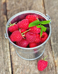 raspberries in a bucket on wooden surface