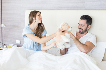 Obraz na płótnie Canvas Couple on Bed with Stuffed Animal Toy