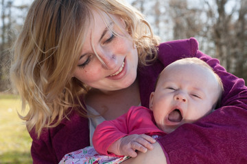 Baby is yawning in mothers arms