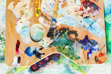 wooden used artistic pallette with paintbrushes