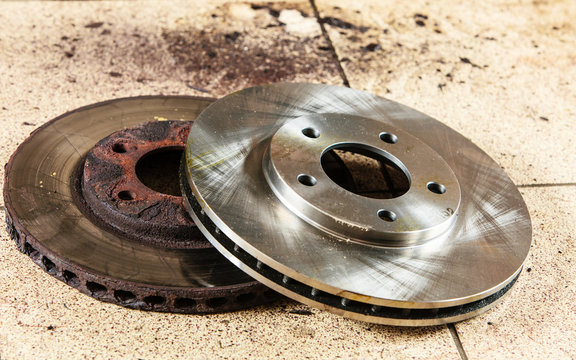Auto in service. New and old front brake disks for modern car.