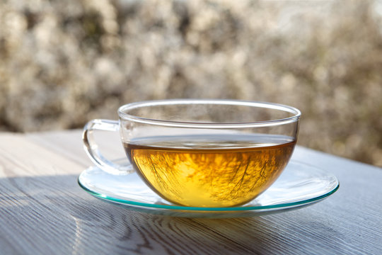 cups of tea on wooden table with blossoming cherry background