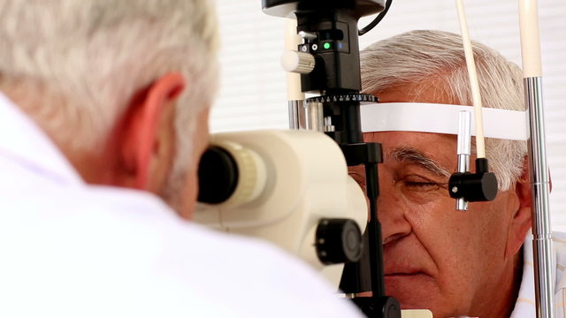 Doctor examining eyes of elderly patient
