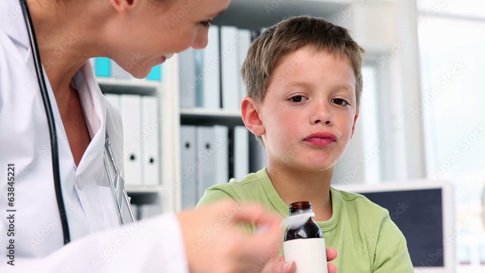 Wall mural Doctor giving little boy a spoon of medicine