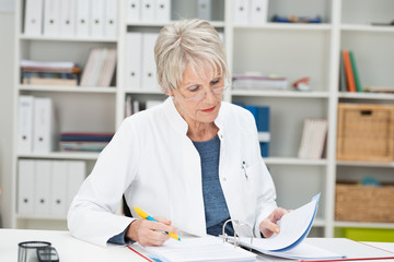 ältere ärztin arbeitet am schreibtisch