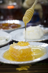 Vertical image of honey dripping from wooden dipper