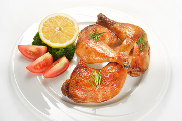Grilled chicken thigh with vegetables on white plate.
