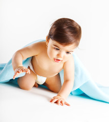 Cute baby girl crawling under blue blanket.