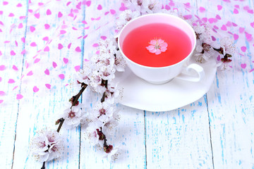 Fragrant tea with flowering branches on wooden table close-up