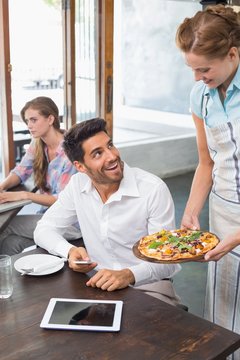 Waitress giving pizza to a man at coffee shop