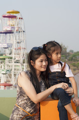 Little Asian girl and mom in amusement park.