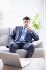 Serious businessman sitting on the couch looking at camera