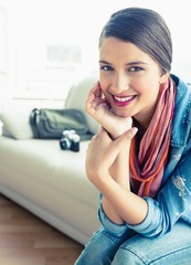 Fototapeta premium Young brunette sitting on sofa looking at camera