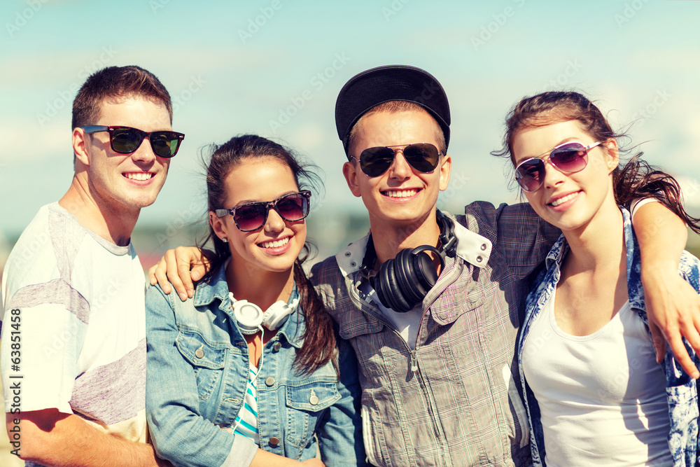 Wall mural smiling teenagers in sunglasses hanging outside