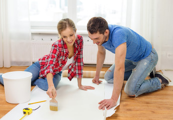 smiling couple smearing wallpaper with glue