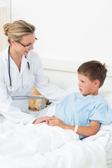 Fototapeta premium Doctor comforting sick boy in hospital