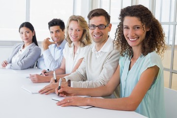 Casual business team smiling at camera sitting at desk