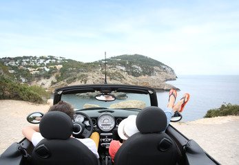 Couple sitting in convertible car and looking at panorama