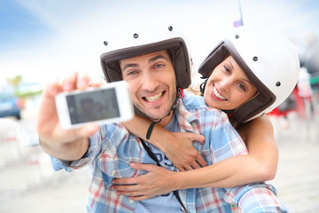 Couple taking picture of themselves on scooter