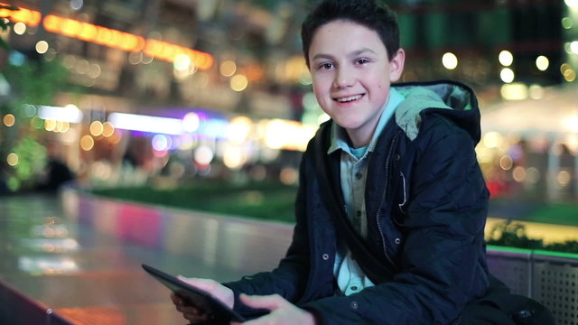 Happy young teenage boy with tablet computer in the city