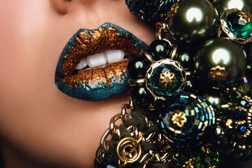Green and golden lips with jewelry. Make up