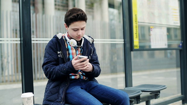 Young teenager waiting for bus on bus stop in the city