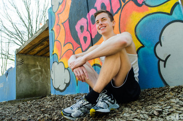 student sitzt vor graffitiwand