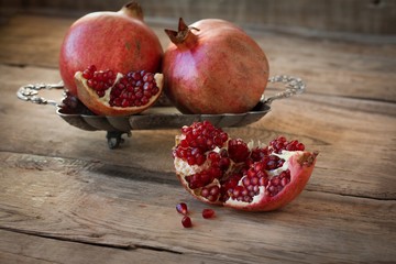 red pomegranates on a plate on old wooden table