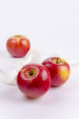 Fototapeta na wymiar Three red apples on white background and ribbon