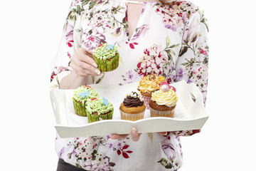 Woman holding tray with colorful cupcakes
