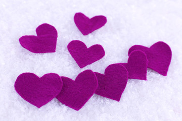Little felt hearts on snowy background