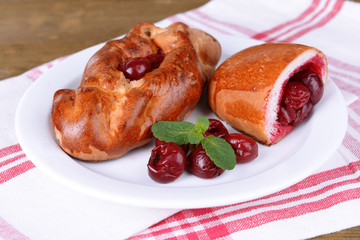 Fresh baked pasties with cherry on plate on table close-up
