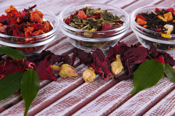 Aromatic dry tea in bowls on wooden background
