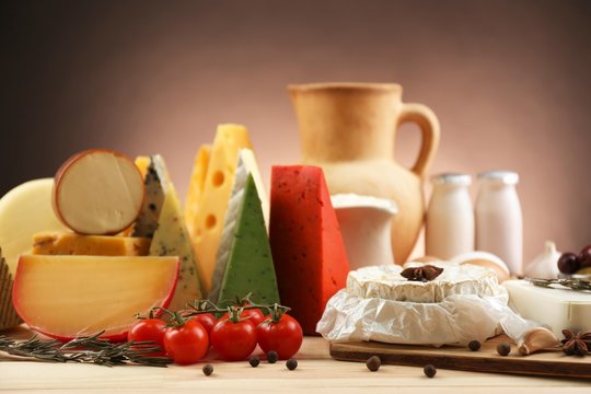 Tasty dairy products on wooden table, on dark background