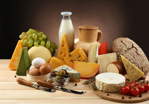 Tasty dairy products on wooden table, on dark background