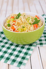 Tasty instant noodles with vegetables in bowl on table close-up