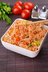 Tasty instant noodles with vegetables in bowl on table close-up
