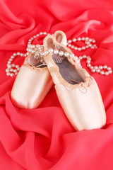 Ballet pointe shoes on red fabric background
