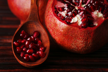 Ripe pomegranate seed in wooden spoon on bamboo mat background