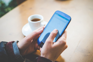 close up of woman hands with smartphone and cup of coffee